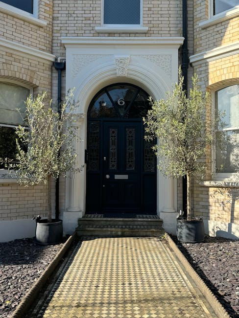 The image depicts a front garden area of a residential property with a neat and well-maintained landscape. The garden features a variety of colorful flowering plants and lush green foliage arranged in